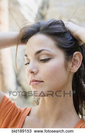 Stock Image - Hispanic woman lifting hair. Fotosearch