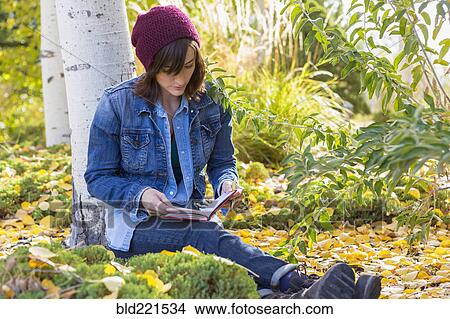 Picture - Hispanic woman reading in garden. Fotosearch