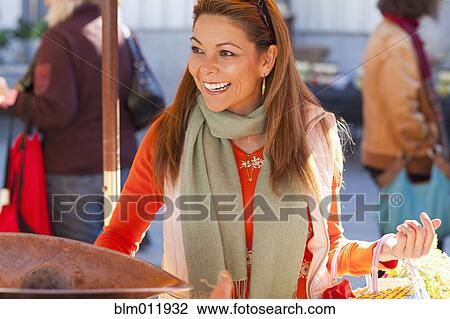 Stock Image - Hispanic woman shopping at farmer's market. Fotosearch
