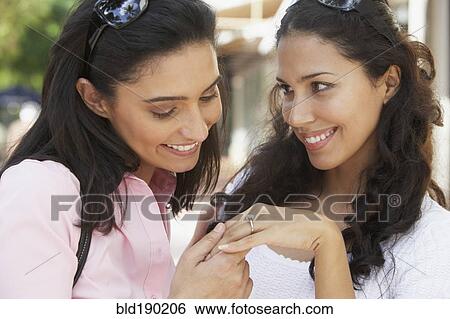Stock Photograph - Hispanic woman showing engagement ring to friend. Fotosearch