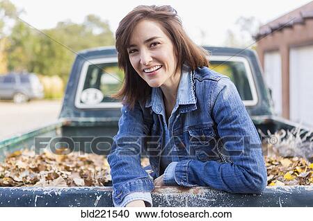 Stock Image - Hispanic woman sitting in truck bed. Fotosearch