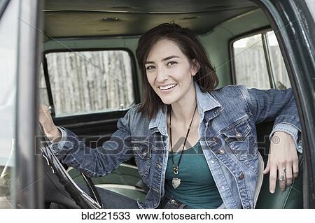 Stock Image - Hispanic woman sitting in truck. Fotosearch