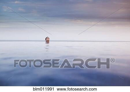 Stock Image - Hispanic woman soaking in swimming pool. Fotosearch