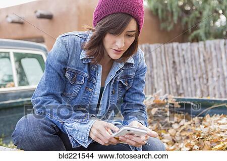 Picture - Hispanic woman using cell phone in truck bed. Fotosearch