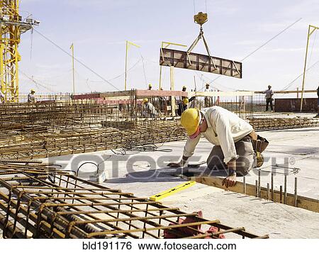 Stock Photograph - Hispanic worker kneeling at construction site. Fotosearch