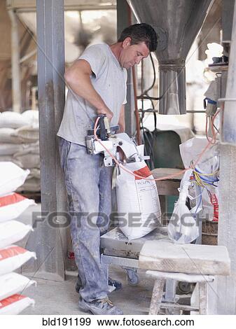 Stock Photo - Hispanic worker sealing bag in factory warehouse. Fotosearch