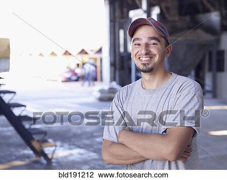 Stock Image - Hispanic worker smiling in factory. Fotosearch