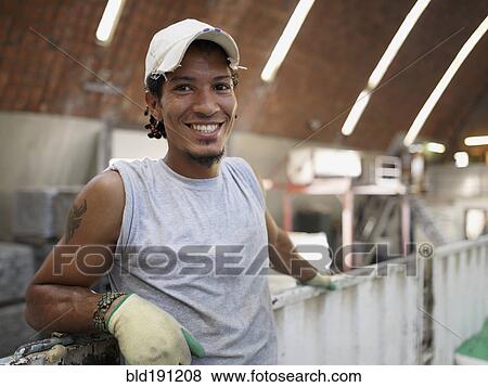 Stock Photo - Hispanic worker smiling in factory. Fotosearch