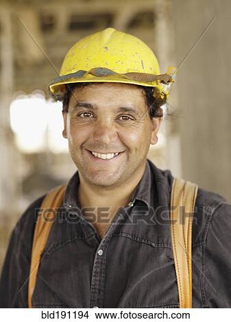 Picture - Hispanic worker smiling on construction site. Fotosearch