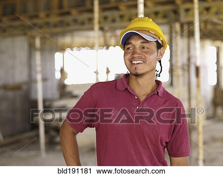 Stock Image - Hispanic worker smiling on construction site. Fotosearch