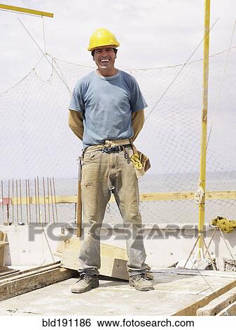 Hispanic worker smiling on construction site View Large Photo Image Stock Photograph - Hispanic worker smiling on construction site. Fotosearch