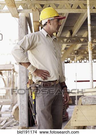 Picture - Hispanic worker standing at construction site. Fotosearch