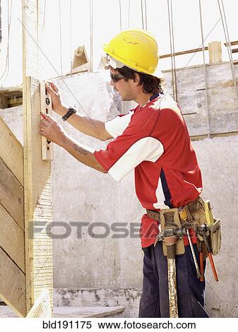 Stock Photography - Hispanic worker using level on construction site. Fotosearch