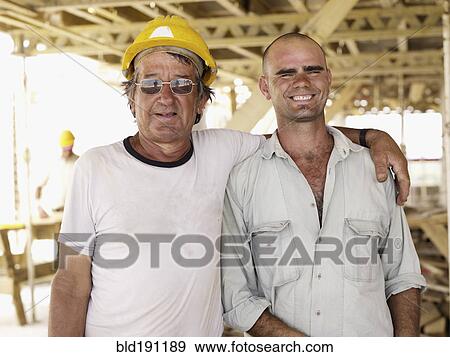 Stock Photo - Hispanic workers hugging construction site. Fotosearch