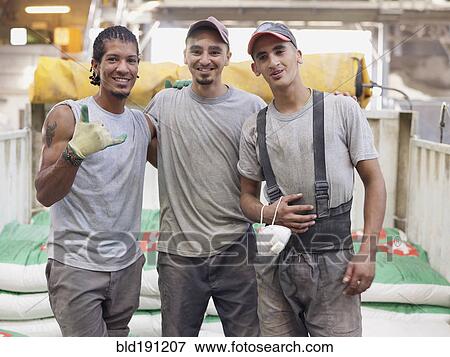 Stock Photo - Hispanic workers hugging in factory. Fotosearch