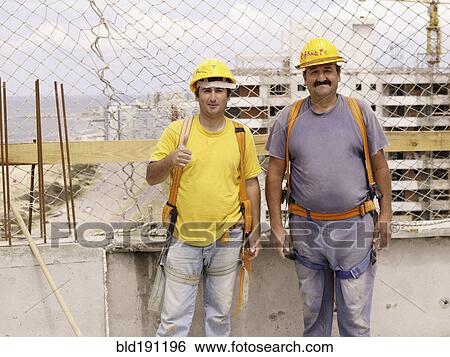 Stock Photograph - Hispanic workers smiling on construction site. Fotosearch
