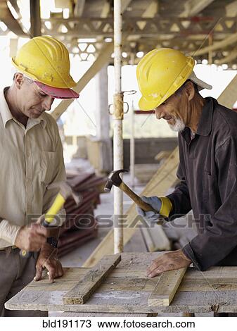 Hispanic workers using hammers at construction site View Large Photo Image Stock Image - Hispanic workers using hammers at construction site. Fotosearch