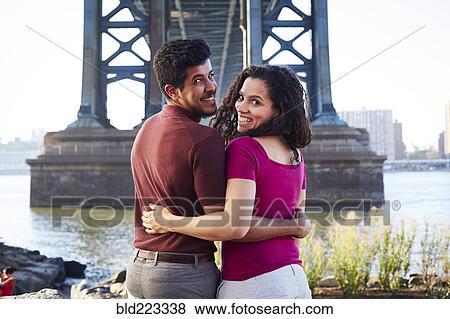 Hugging couple smiling at waterfront View Large Photo Image Stock Photo - Hugging couple smiling at waterfront. Fotosearch