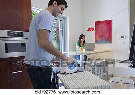 Husband ironing while wife uses laptop View Large Photo Image Stock Photograph - Husband ironing while wife uses laptop. Fotosearch