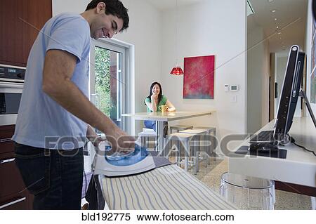 Husband ironing while wife watches View Large Photo Image Stock Photography - Husband ironing while wife watches. Fotosearch