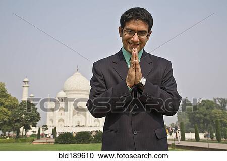 Stock Image - Indian businessman praying at the Taj Mahal. Fotosearch