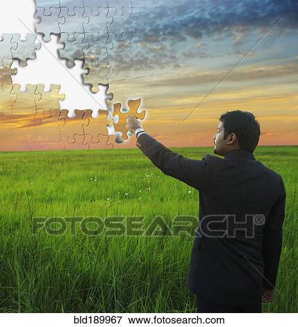 Stock Photo - Indian businessman putting piece in jigsaw puzzle sky. Fotosearch