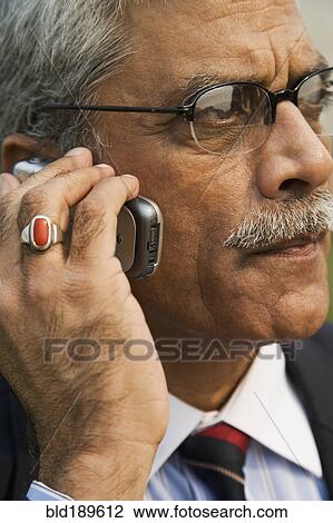Stock Image - Indian businessman talking on cell phone. Fotosearch