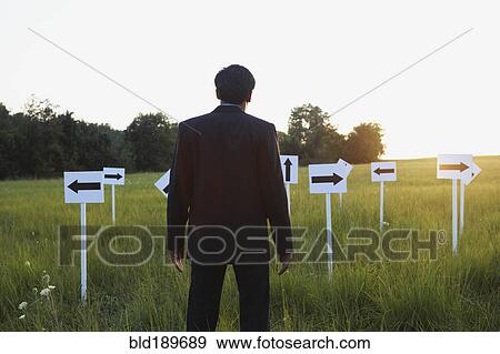 Stock Photo - Indian businessman with arrow signs in field. Fotosearch