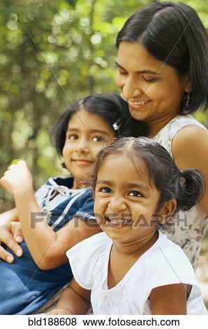 Stock Photo - Indian mother sitting with daughters outdoors. Fotosearch