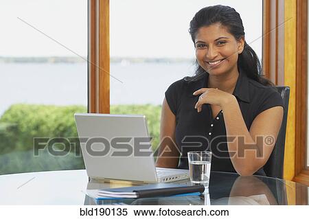 Indian woman at table with laptop View Large Photo Image Stock Photography - Indian woman at table with laptop. Fotosearch