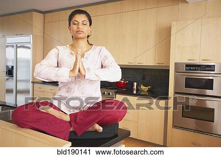 Indian woman meditating in kitchen View Large Photo Image Stock Image - Indian woman meditating in kitchen. Fotosearch