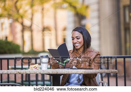 Indian woman reading booklet at outdoor cafe View Large Photo Image Stock Photograph - Indian woman reading booklet at outdoor cafe. Fotosearch