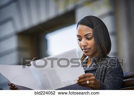 Indian woman sitting on city bench reading paperwork View Large Photo Image Stock Image - Indian woman sitting on city bench reading paperwork. Fotosearch