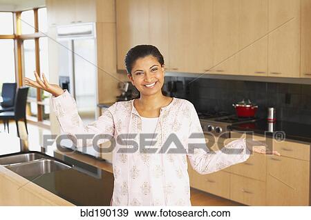 Stock Photo - Indian woman standing in kitchen. Fotosearch