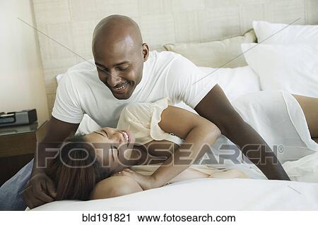 Stock Image - Intimate couple laying on bed. Fotosearch