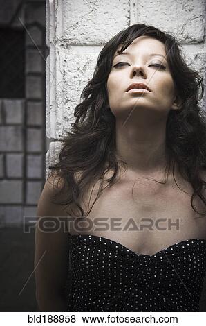 Stock Photo - Italian woman leaning against wall with eyes closed. Fotosearch