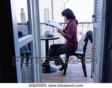 Stock Image - Japanese woman reading map on balcony. Fotosearch