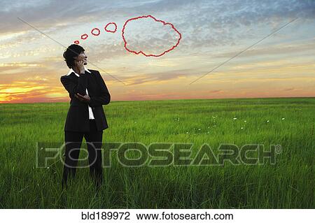 Stock Image - Kazakh businesswoman in field with thought bubble. Fotosearch