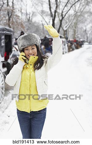 Stock Image - Korean woman talking on cell phone on snowy day. Fotosearch