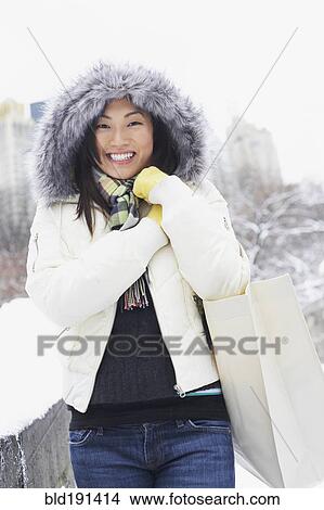 Picture - Korean woman walking with bag in snow. Fotosearch