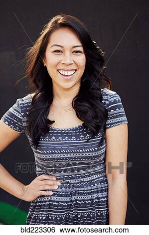 Stock Photograph - Laughing Pacific Islander woman standing with hand on hip. Fotosearch