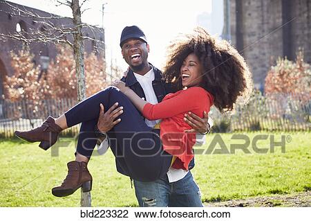 Stock Image - Man carrying woman and laughing. Fotosearch