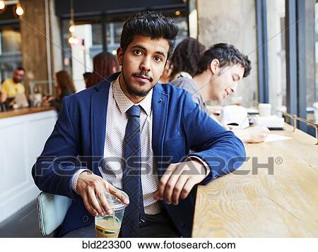 Stock Image - Man drinking cold beverage in cafe. Fotosearch