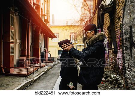 Stock Image - Man holding head of woman in urban alley. Fotosearch