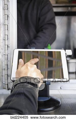 Stock Photography - Man paying at food cart using digital tablet. Fotosearch