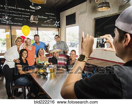 Man photographing friends in cafe View Large Photo Image Stock Photograph - Man photographing friends in cafe. Fotosearch