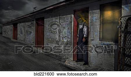 Stock Image - Man standing in dilapidated building doorway. Fotosearch