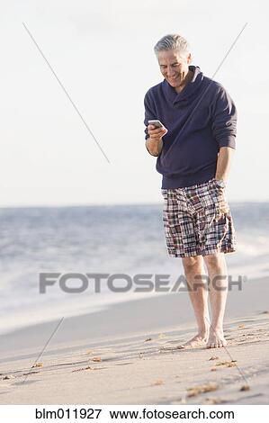 Man using cell phone on beach View Large Photo Image Stock Photo - Man using cell phone on beach. Fotosearch