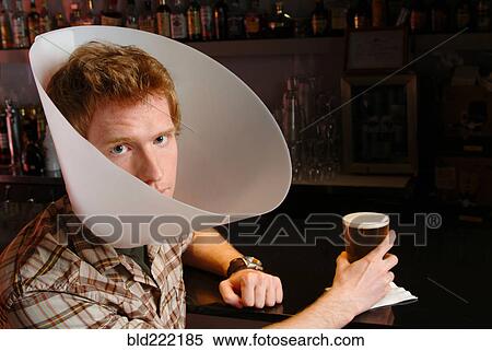 Stock Photography - Man wearing medical cone in bar. Fotosearch