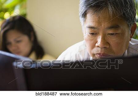 Stock Photo - Mature Asian man reading book. Fotosearch
